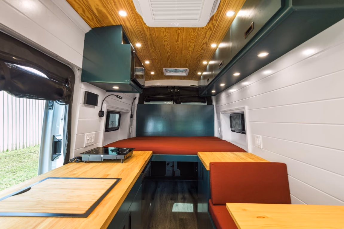 Camper van fixed bed, tinted bunk windows, and open storage space beneath the mattress.