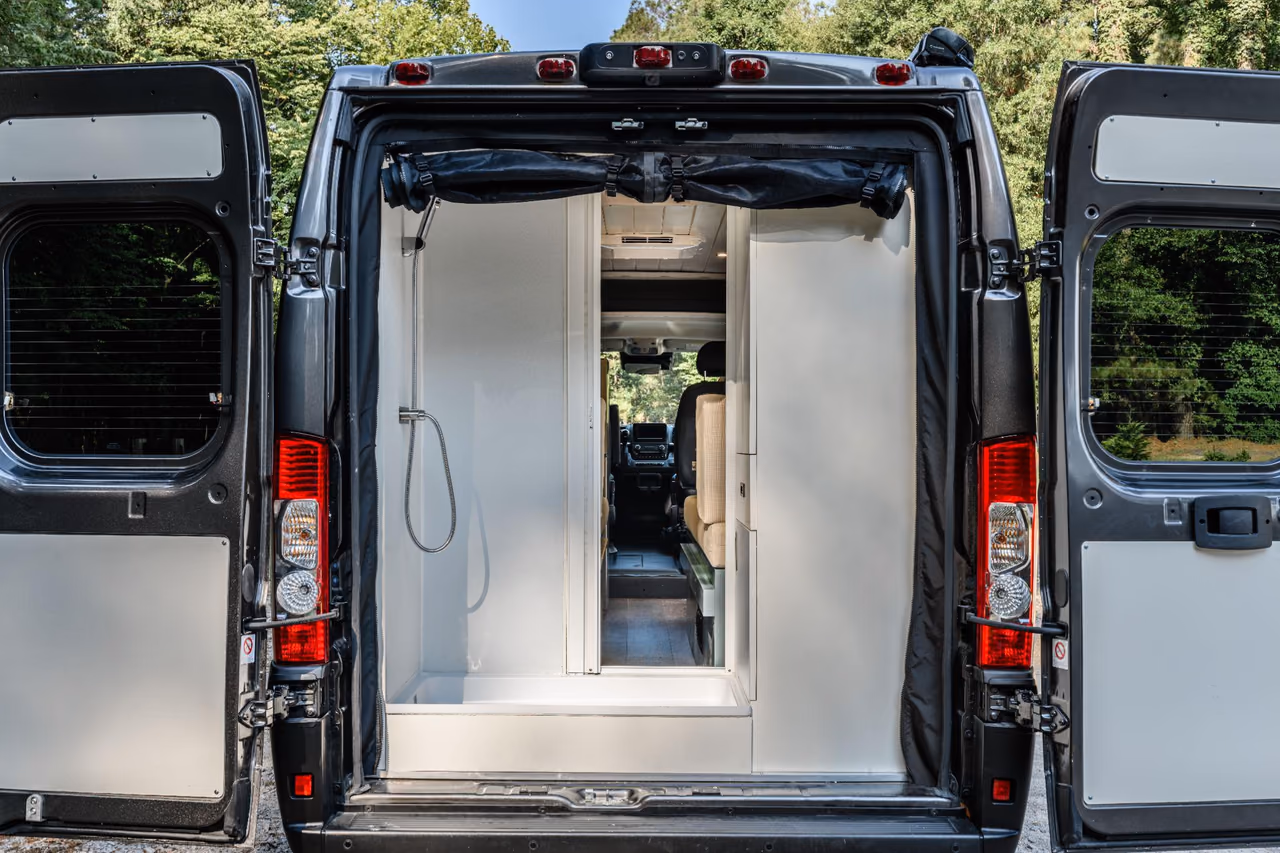 Rear view of a custom camper van with the doors open to reveal a spacious built-in shower.