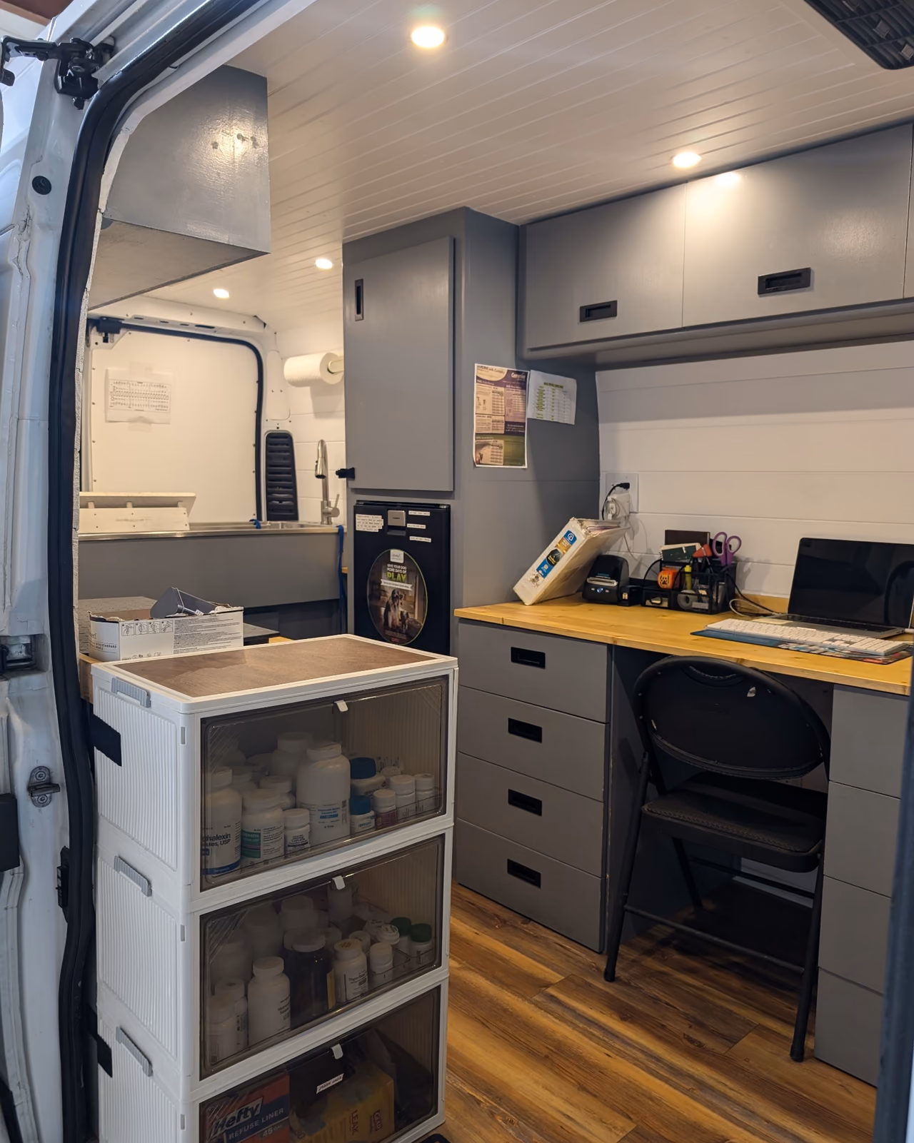 Mobile veterinary clinic in daily use with medical supplies organized beside the built-in desk and cabinetry.